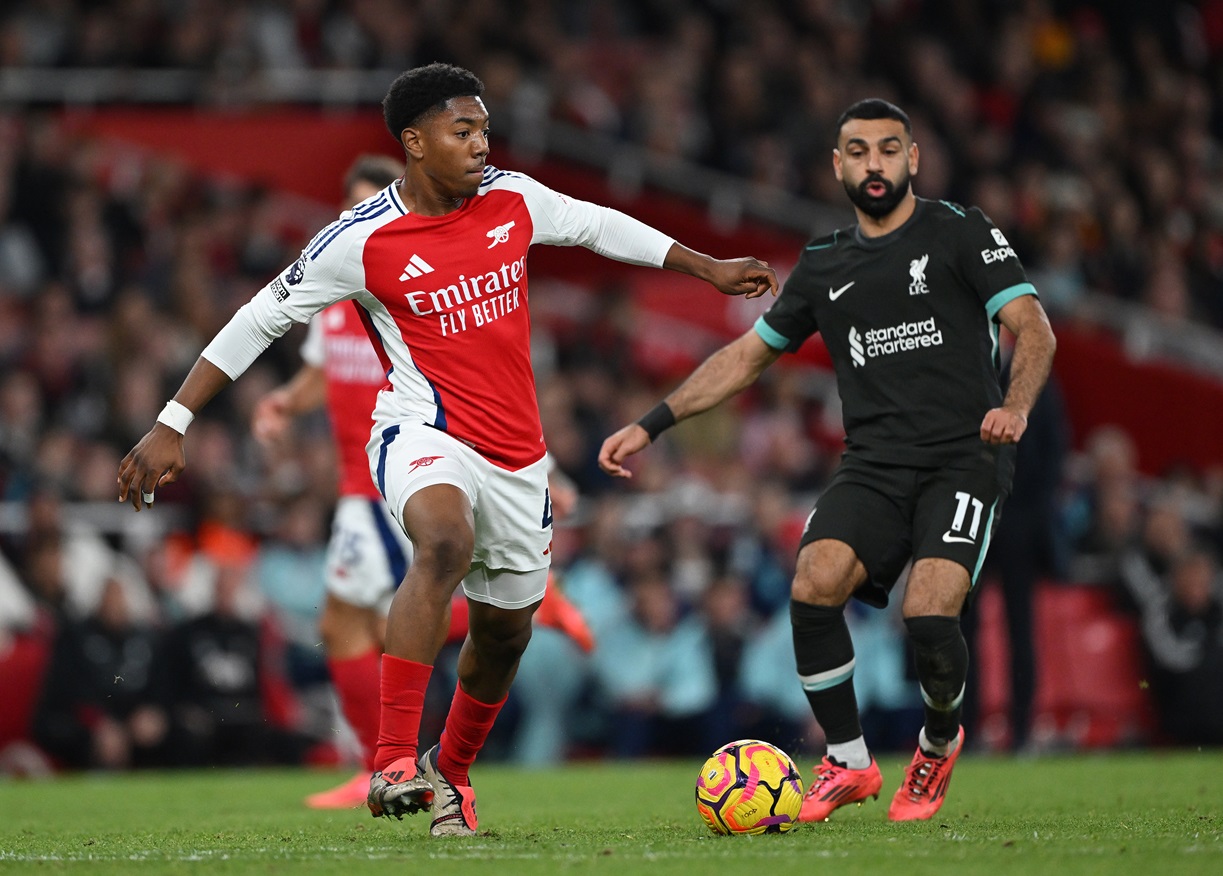 Myles Lewis-Skelly of Arsenal passes the ball as Mohamed Salah of Liverpool looks on